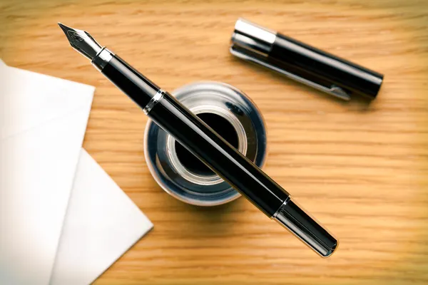 Fountain pen and inkwell on desk — Stock Photo, Image