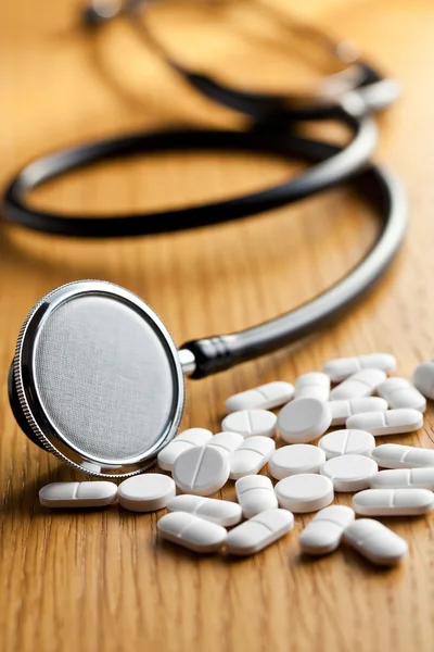 White pills with stethoscope — Stock Photo, Image