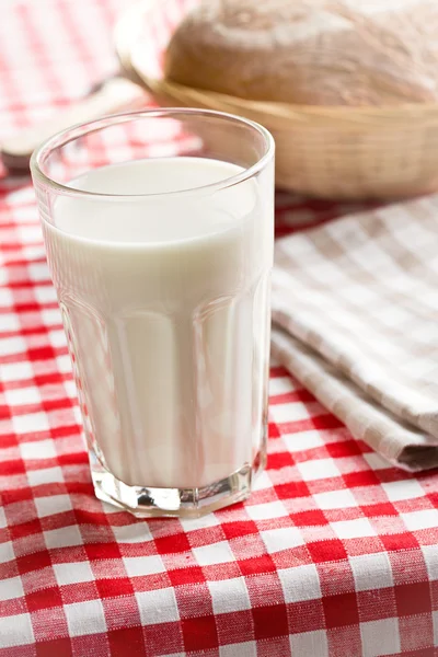 Glass of milk on checkered tablecloth — Stock Photo, Image
