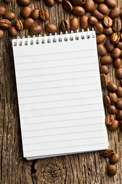 Spiral notebook and coffee beans — Stock Photo, Image