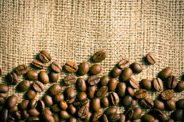 Grains de café sur fond de toile de jute — Photo