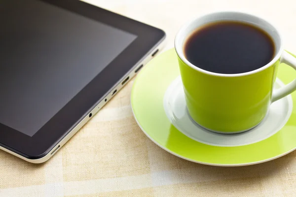 black coffee in green cup with computer tablet