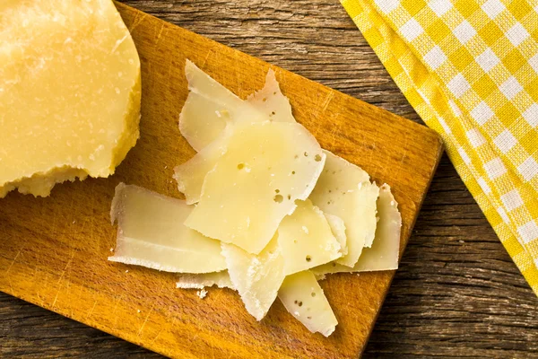 Kousky italský tvrdý sýr na dřevěný stůl — Stock fotografie