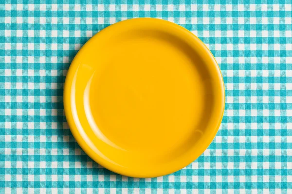 Empty plate on checkered tablecloth — Stock Photo, Image