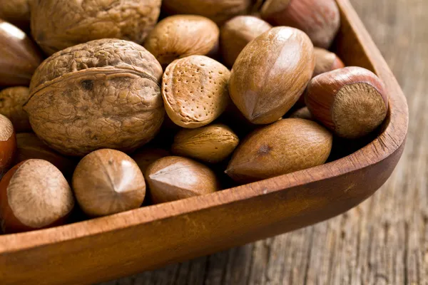 Various unpeeled nuts in wooden bowl — Stock Photo, Image