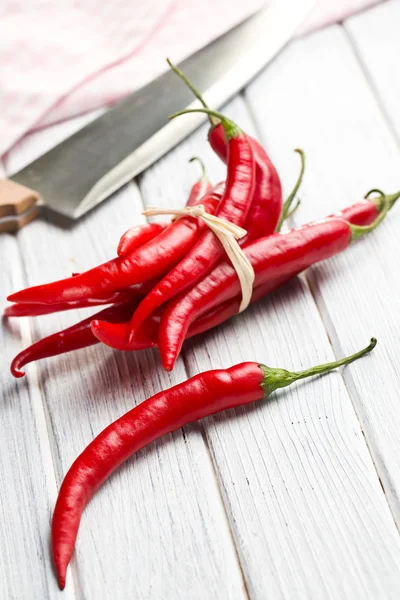 Svázané chili peppers na dřevěné pozadí — Stock fotografie