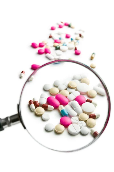 Pills under magnifying glass — Stock Photo, Image