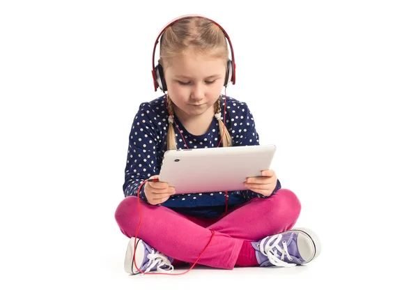 Маленькая девочка с планшетом и наушниками — стоковое фото