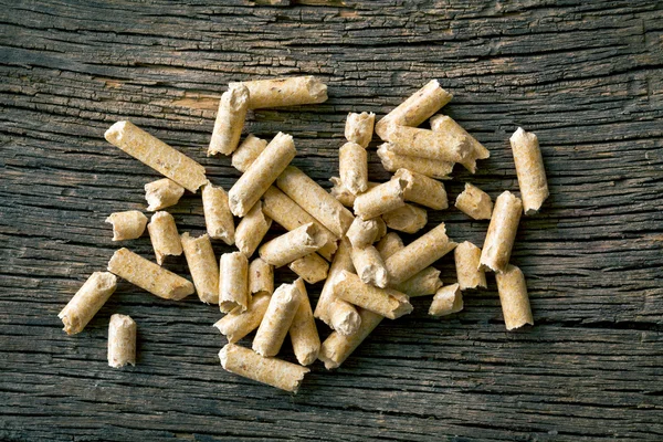 Wooden pellets on old wooden background — Stock Photo, Image