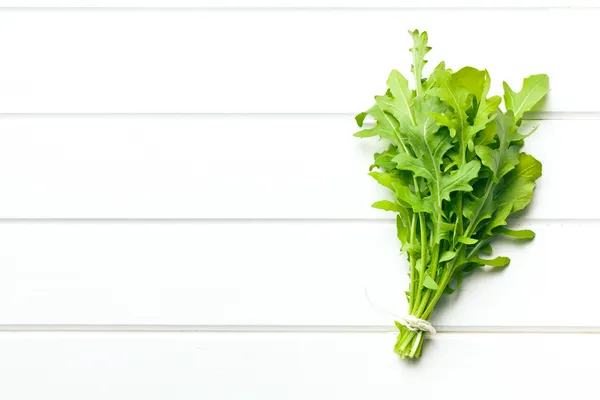 Fresh arugula leaves on kitchen table — Stock Photo, Image