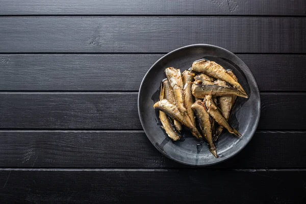 Smoked Sprats Plate Canned Sea Fish Black Table Top View — Stock Photo, Image