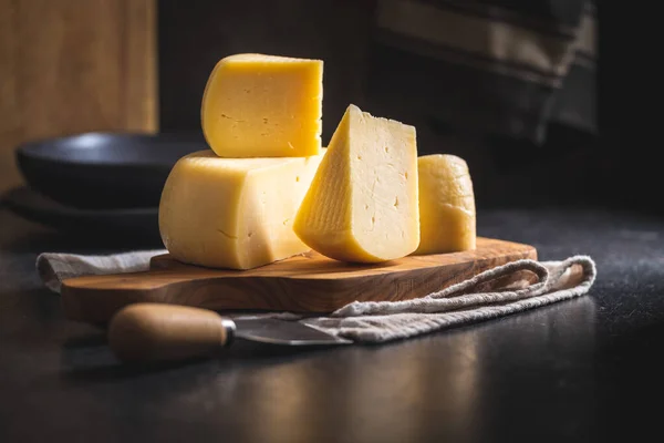 ハードチーズのブロック まな板の上でチーズをスライス — ストック写真
