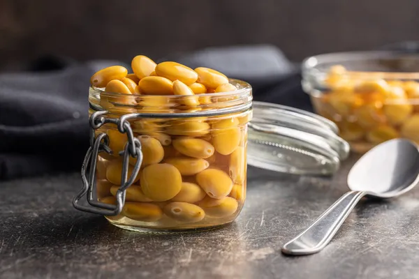 在厨房桌子上的罐子里挑逗的黄色卢平豆子 — 图库照片