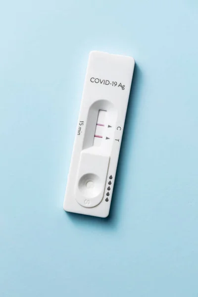 Positive Covid-19 antigen test. Coronavirus antigen rapid test on blue background. Top view.