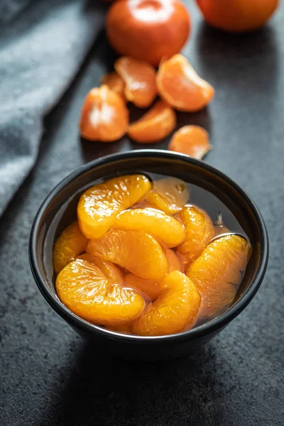 罐装橘子 在黑桌上的碗里 煮好的芒果 — 图库照片