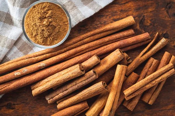 Dry cinnamon sticks and cinnamon powder on a wooden table. Top view. Cinnamon spice.