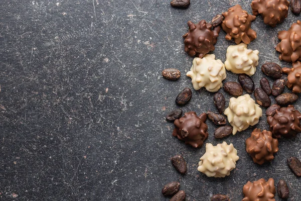 チョコレートトリュフとココア豆 黒のテーブルの上の甘いプラリネ トップ表示 — ストック写真