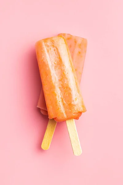Fruity ice lolly. Sweet popsicle on a pink table. Top view.