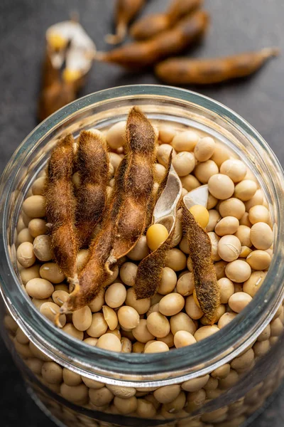 Soy beans . Dried soybean pod in jar on the black table.