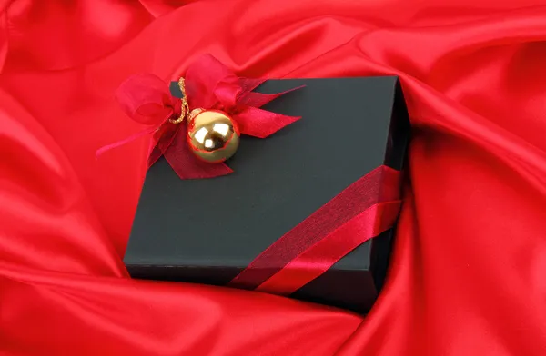 Black gift box with gold bauble — Stock Photo, Image