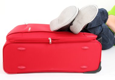 Young man lies on the red suitcase clipart