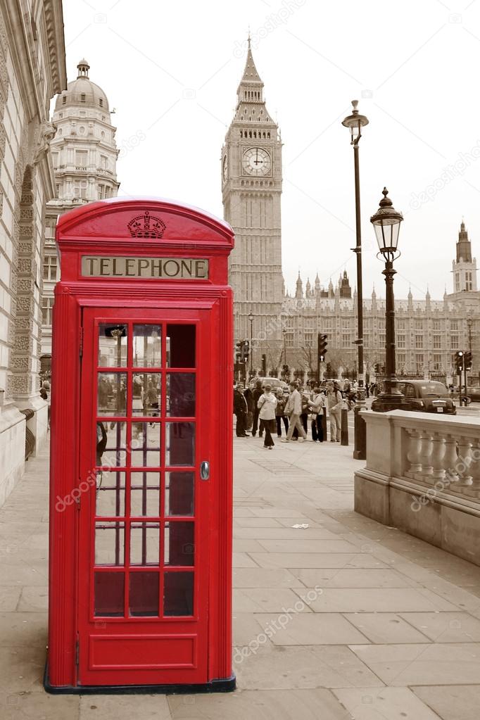 A traditional red phone booth in London with the Big Ben in a sepia background