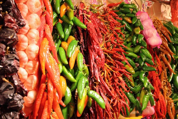 Hangende trossen van rode en groene paprika's en garlics, op een markt in Spanje — Stockfoto