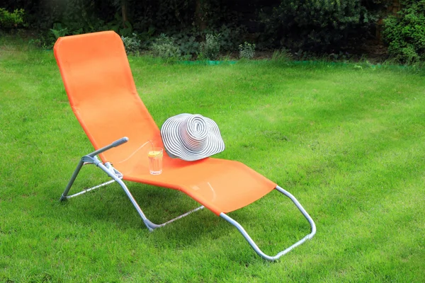 Orange lounge sunbed standing on green grass — Stock Photo, Image