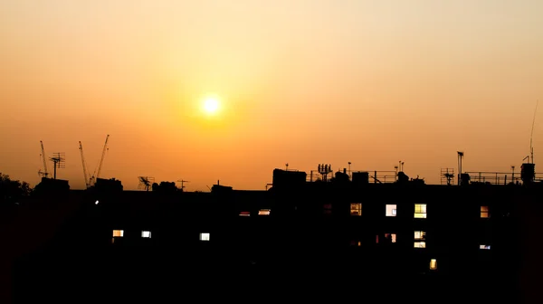 Puesta de sol sobre tejados con luces de construcción —  Fotos de Stock