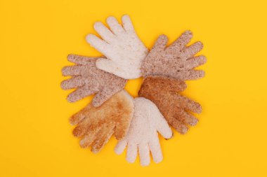 Multicultural hands together in a circle made from bread on a yellow background
