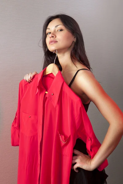 Женщина, которая примеряет красную рубашку в магазине — стоковое фото