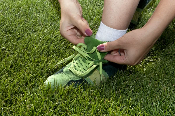 Женщина завязывает шнурки на зеленые туфли — стоковое фото