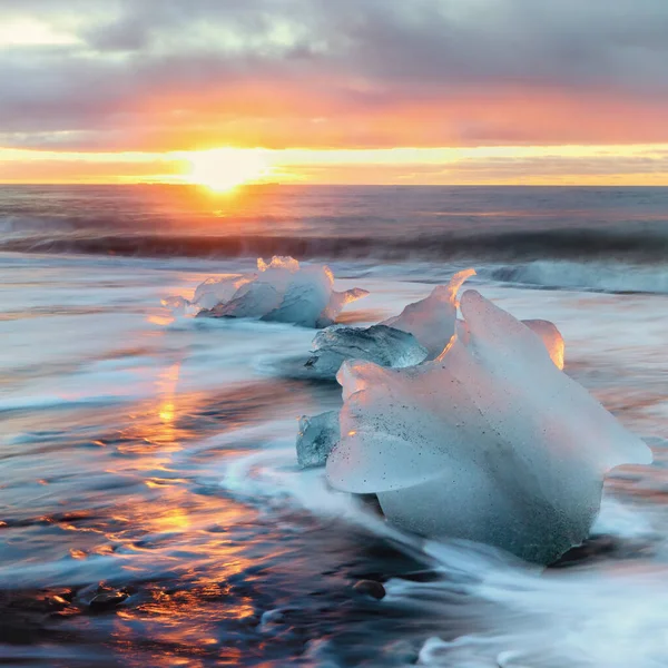 冰岛南部Vatnajokull的钻石海滩 太阳升起在黑色沙滩上的大块冰块上 这些冰块已经从乔库沙伦冰川泻湖中消失在海滩上了 — 图库照片