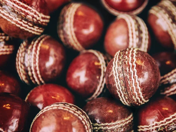 A background of vintage red leather cricket balls with white stitching. Retro style processing.