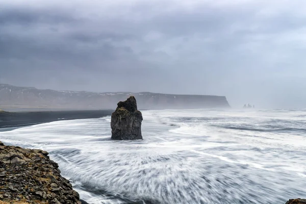 冰岛南部Dyrholaey的Arnardrangur或Eagle Rock 这块岩石之所以这么叫是因为老鹰曾经在它上面筑巢 长期暴露的成分 背景为雷诺斯兰加和雷诺斯法哈拉 — 图库照片
