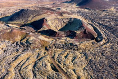 Extinct volcano crater and the lava fields of the Berserkjahraun region, Snaefellsnes Peninsula, Iceland. A dirt road can be seen winding through the area. High angle view drone shot. clipart