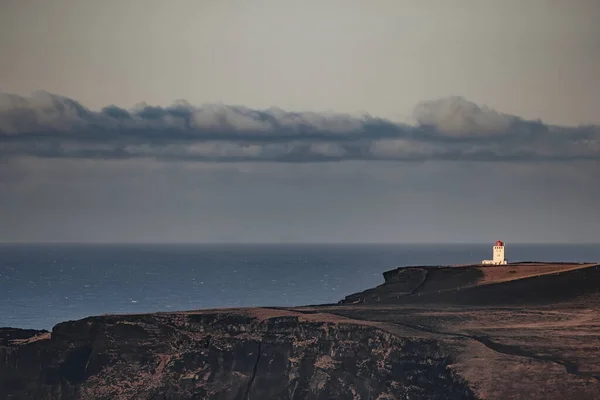 Dyrholaey Lighthouse stands on the rugged cliffs of the Southern iceland. Sea view in autumn with the Atlantic Ocean in the background.