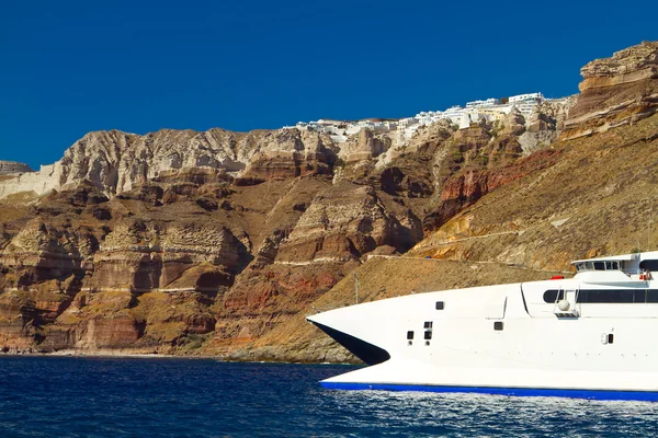 Boat at high volcanic cliff of Santorini island — Stock Photo, Image