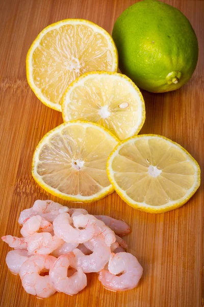 Сырые креветки с ломтиками лимона для приготовления пищи — стоковое фото