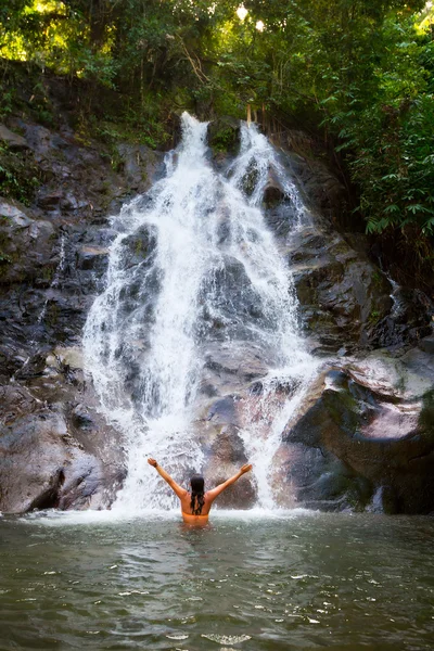 Woman refreshing herself in beautiful waterfall — Stock Photo, Image