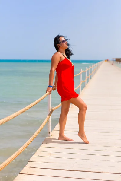 Kızıldeniz iskeleye Kırmızı elbiseli güzel kadın — Stok fotoğraf