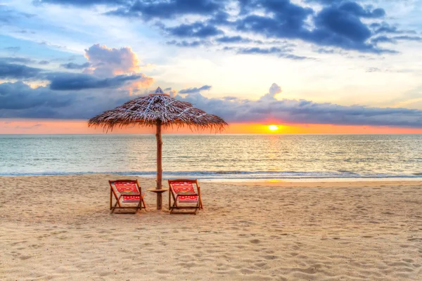 Zonsondergang onder parasol op het strand — Stockfoto