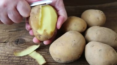 Hands peeling potato on rustic wooden table