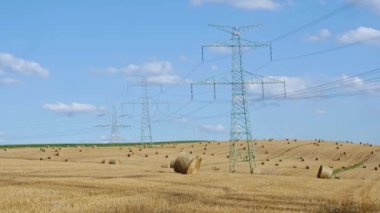 Yüksek elektrik direklerinin yanındaki alanda saman balyaları