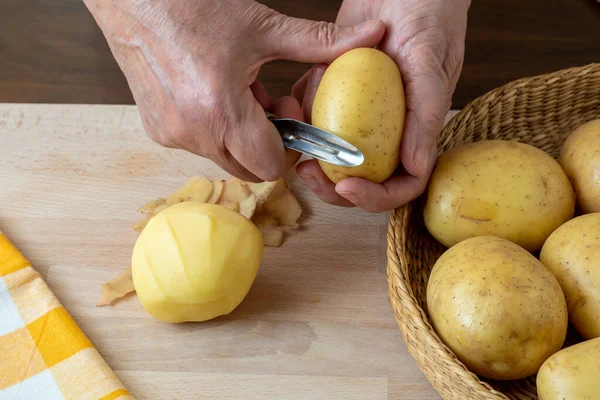 Hands Peel Potato Peelings Wooden Cutting Board — Fotografia de Stock