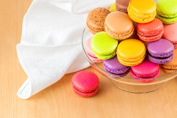 Traditional french colorful macarons in a glass cake stand on wooden table — Stock Photo, Image