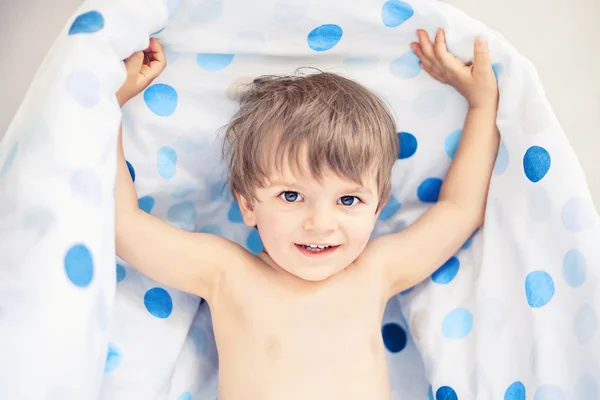 Niño sonriente sosteniendo la manta después de dormir —  Fotos de Stock