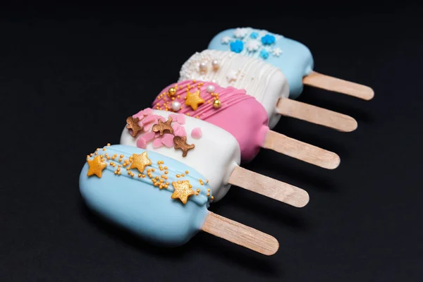 黒の背景の行に5つの装飾されたケーキのポップアイスクリーム — ストック写真