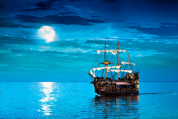 Pirate ship sailing under the full Moon