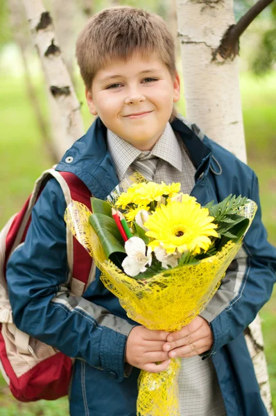 Школьник с букетом жёлтых хризантем в парке — стоковое фото